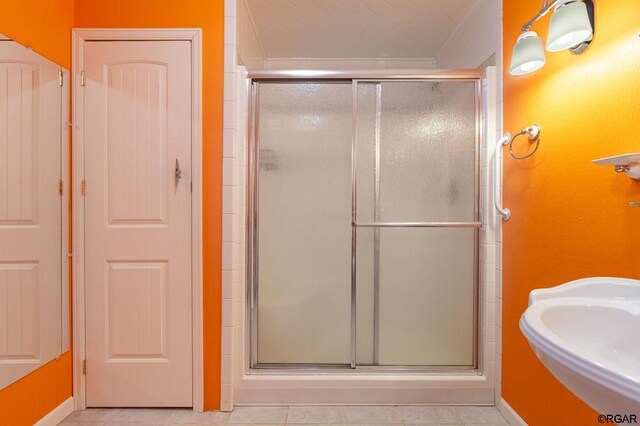 bathroom with an enclosed shower, sink, and tile patterned flooring