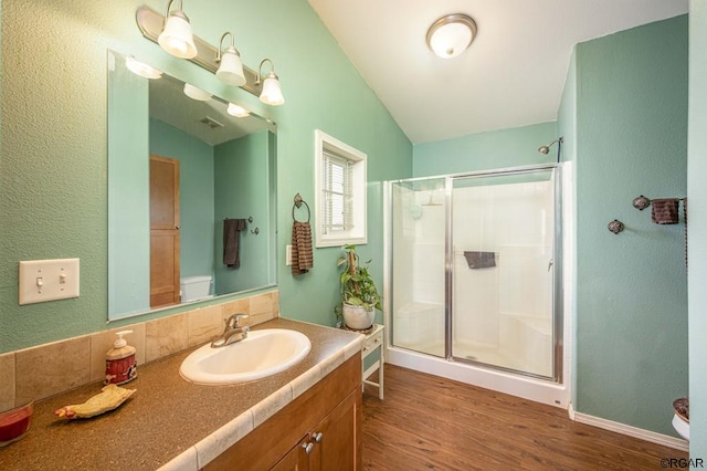 bathroom with a shower with door, vaulted ceiling, hardwood / wood-style floors, and toilet