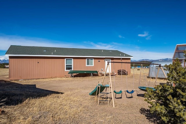 back of property featuring a playground and a water and mountain view