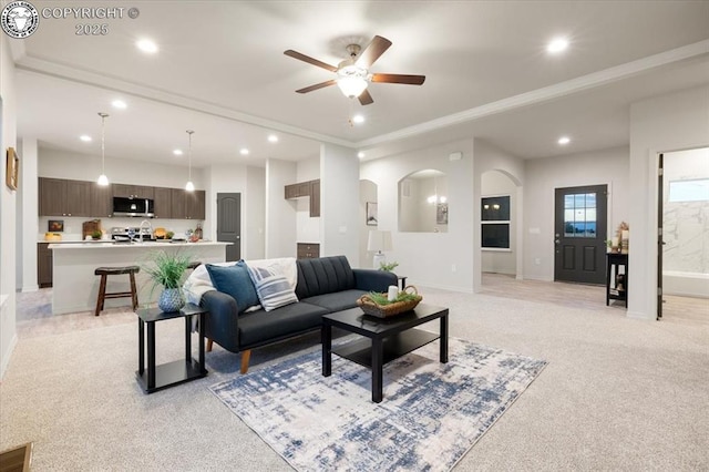 carpeted living room with ornamental molding and ceiling fan