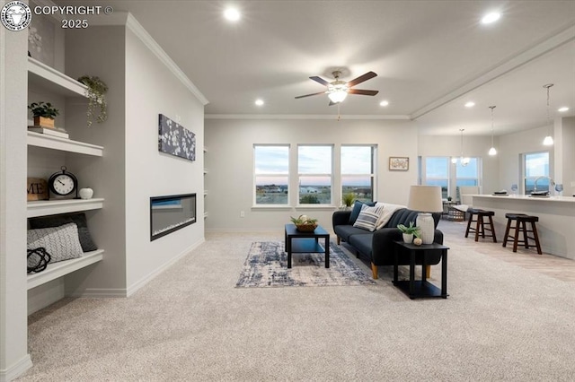 carpeted living room with crown molding, ceiling fan with notable chandelier, and built in shelves