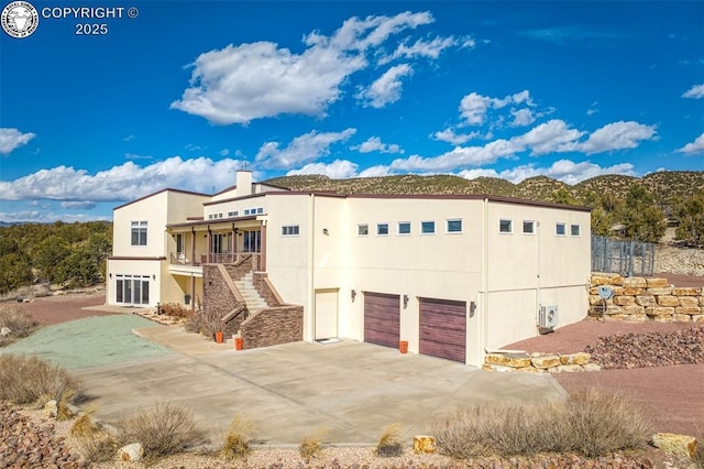 view of front of property with a chimney, stucco siding, stairway, an attached garage, and driveway