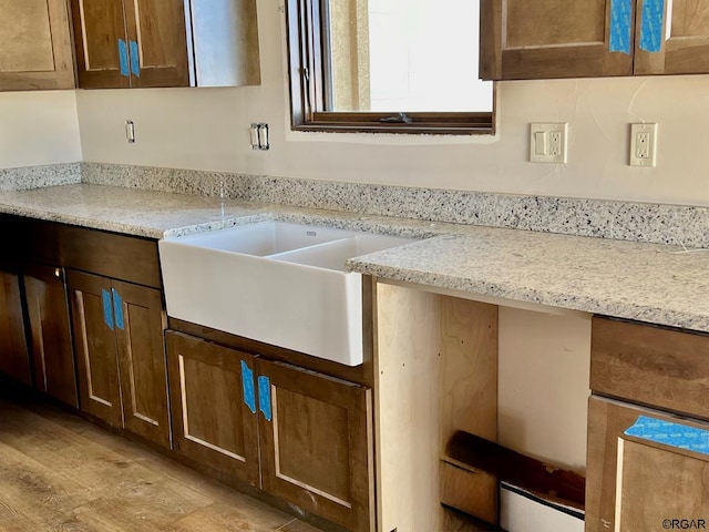 kitchen featuring light stone countertops, sink, and light hardwood / wood-style floors