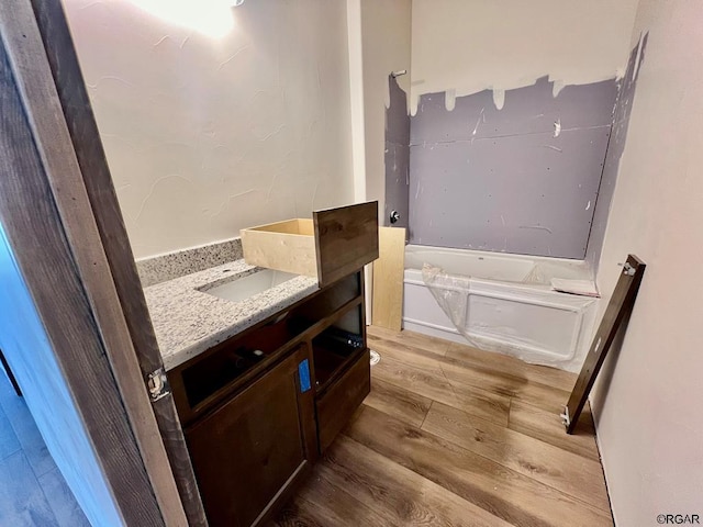 bathroom featuring wood-type flooring, a bathtub, and vanity