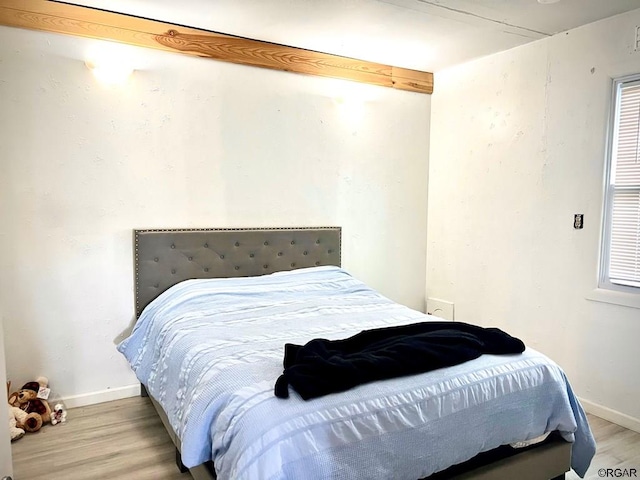 bedroom featuring beam ceiling and light wood-type flooring