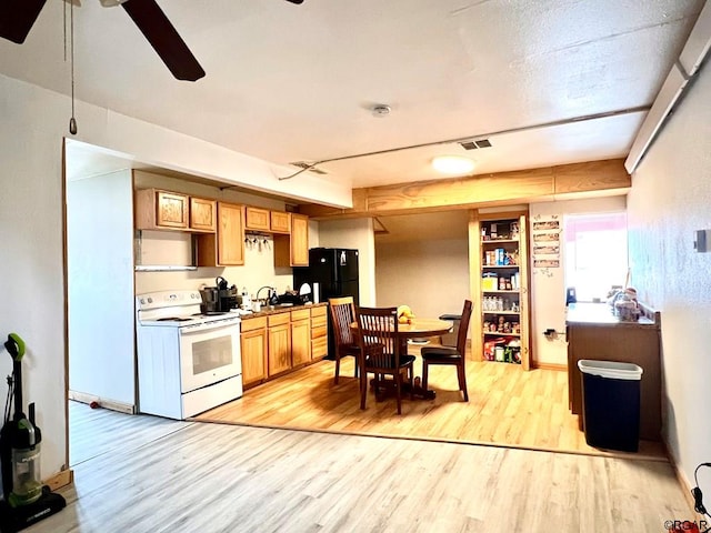 kitchen featuring white electric range oven, sink, black fridge, ceiling fan, and light hardwood / wood-style floors