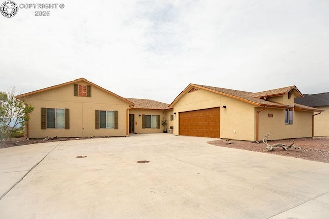 single story home featuring a garage, concrete driveway, and stucco siding