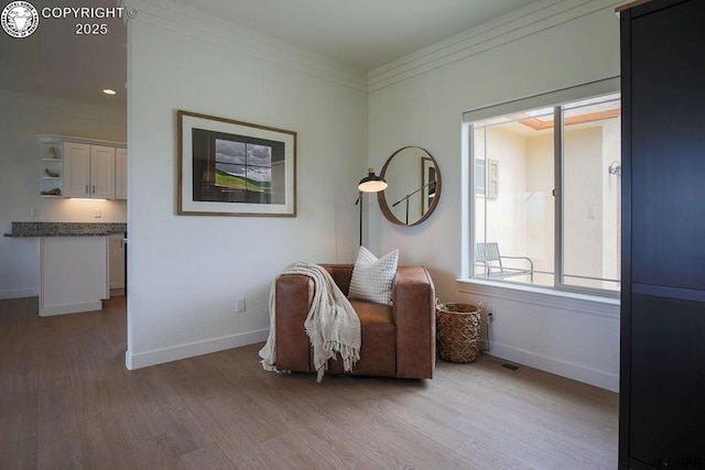 sitting room featuring light wood-type flooring, visible vents, crown molding, and baseboards