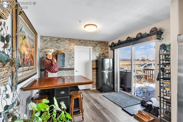 kitchen featuring black fridge, hardwood / wood-style floors, and a textured ceiling