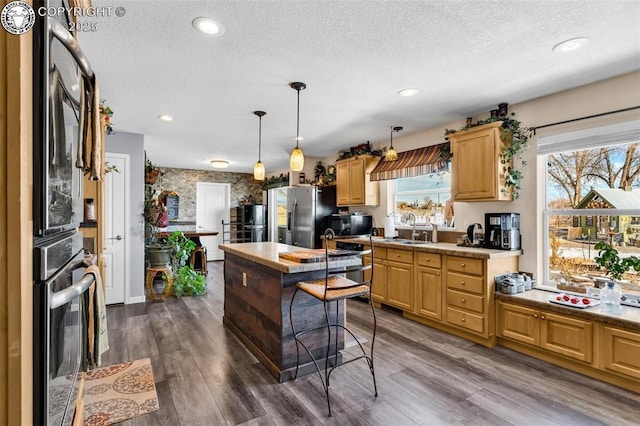 kitchen with pendant lighting, sink, stainless steel appliances, dark wood-type flooring, and light brown cabinets