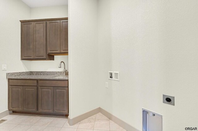 washroom with sink, cabinets, light tile patterned floors, hookup for a washing machine, and hookup for an electric dryer