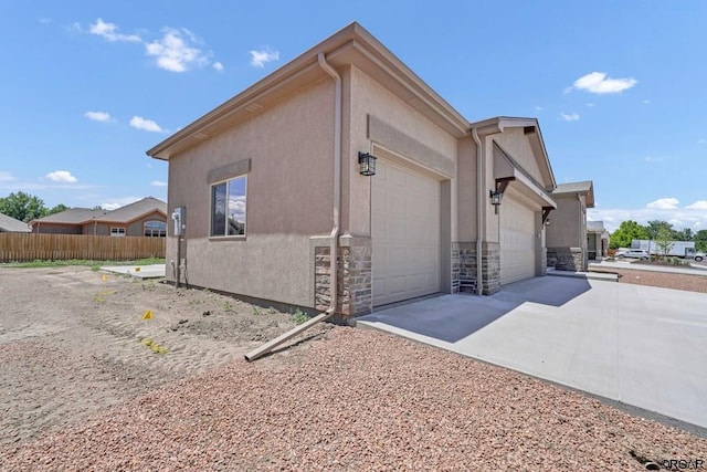 117 Rocchio Dr, Florence, CO 81226 - view of property exterior featuring fence, an attached garage, stone siding, driveway, and stucco siding