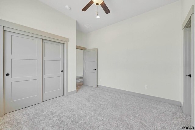 unfurnished bedroom with light carpet, ceiling fan, and a closet