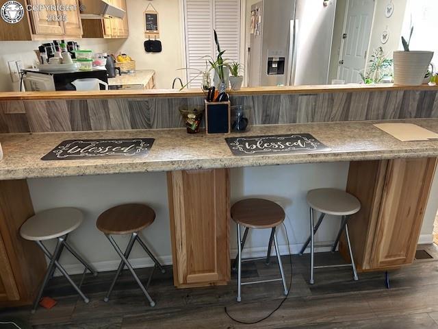 600 Raintree Blvd Unit 76, Canon City, CO 81212 - kitchen with stainless steel fridge, extractor fan, dark wood-style flooring, a breakfast bar area, and light countertops