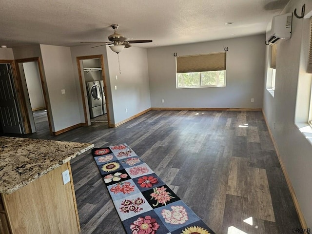 unfurnished living room featuring washing machine and clothes dryer, dark wood-style floors, a wall mounted AC, and baseboards