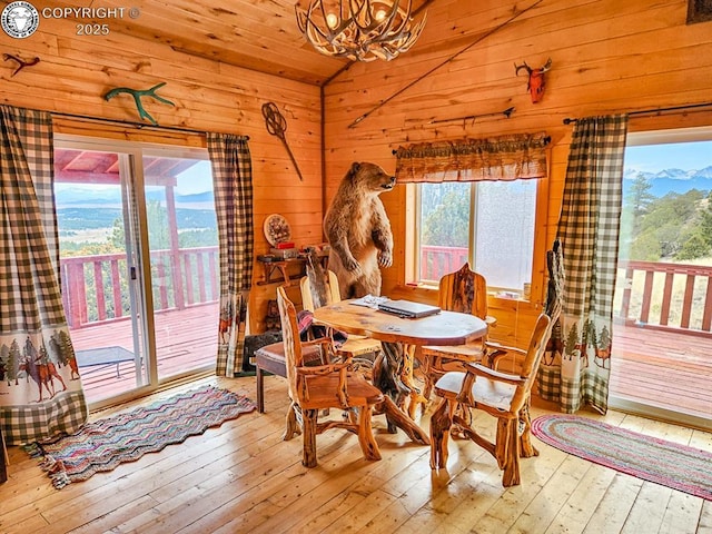 297 S Matterhorn Cir, Westcliffe, CO 81252 - dining area with an inviting chandelier, vaulted ceiling, wood walls, and hardwood / wood-style floors