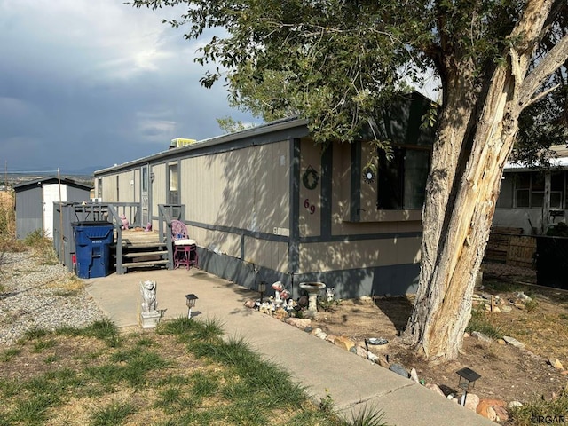 view of side of home featuring a wooden deck and a storage shed