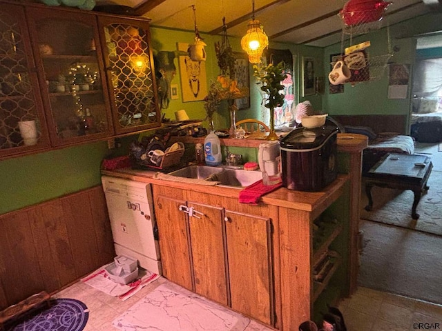 kitchen featuring dishwasher, sink, pendant lighting, and wooden walls