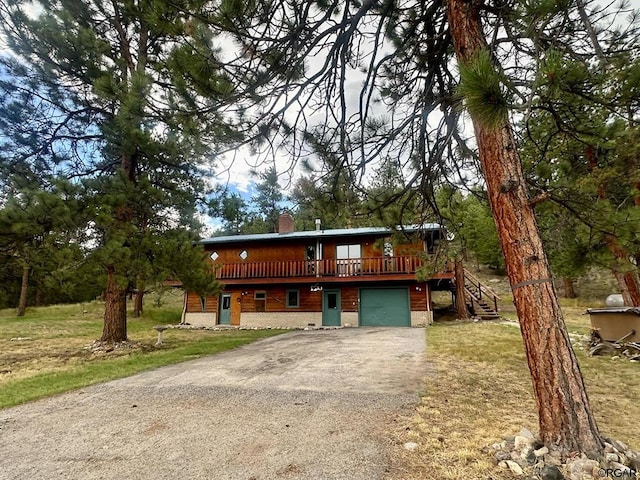 view of front of home with a garage, a deck, and a front yard