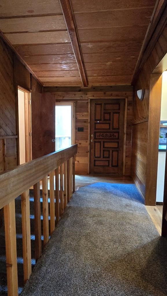 corridor with wood ceiling, carpet flooring, wooden walls, and beamed ceiling