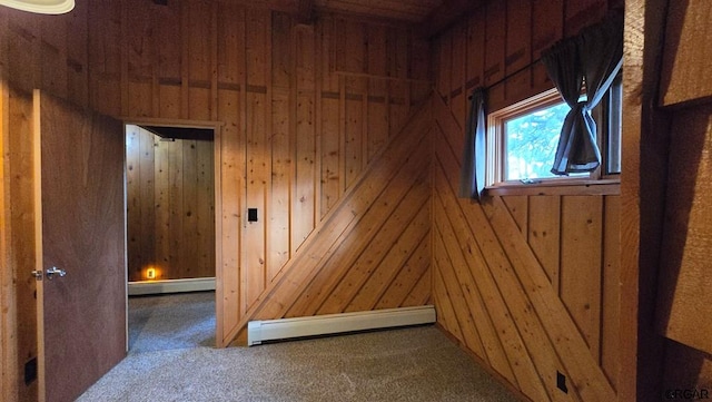 carpeted spare room with a baseboard heating unit and wood walls