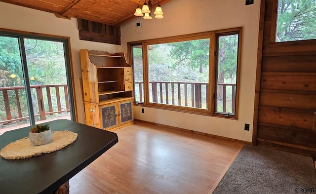 dining area with plenty of natural light, light wood-type flooring, wooden ceiling, and a chandelier