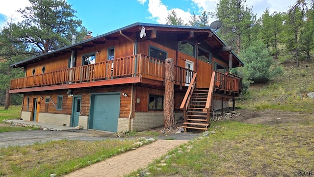 rear view of house featuring a wooden deck and a garage