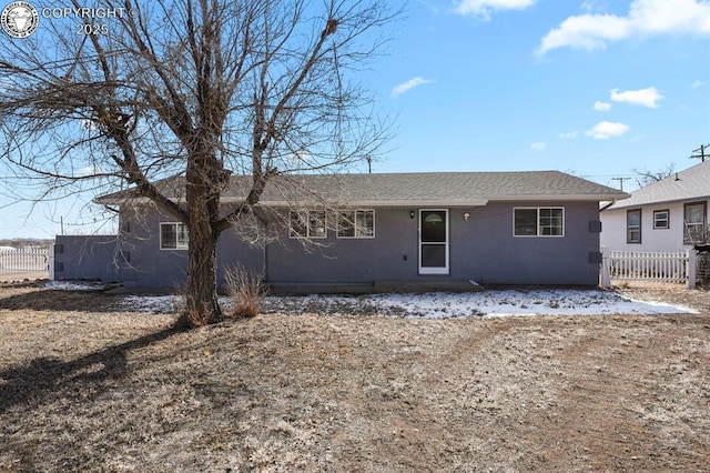 view of front of home with roof with shingles, fence, and stucco siding