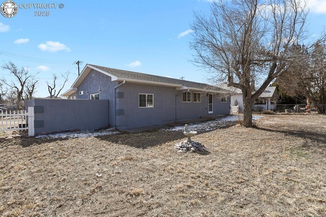 view of side of home featuring fence and stucco siding