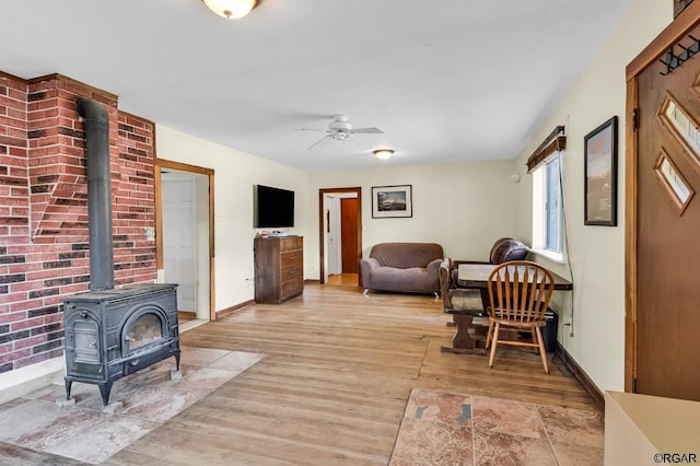 sitting room with a wood stove, ceiling fan, and light hardwood / wood-style flooring