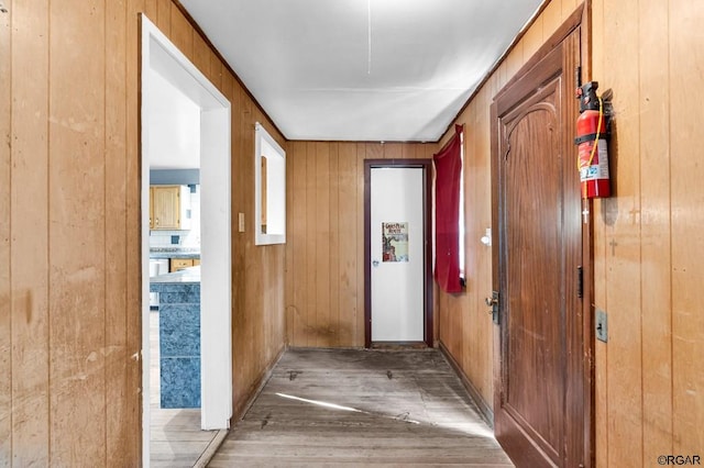 corridor featuring wood-type flooring and wooden walls