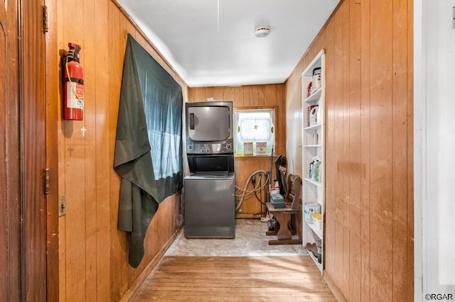 kitchen featuring stacked washing maching and dryer, wooden walls, and light hardwood / wood-style floors