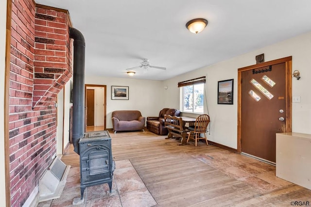 living room featuring ceiling fan, hardwood / wood-style floors, and a wood stove