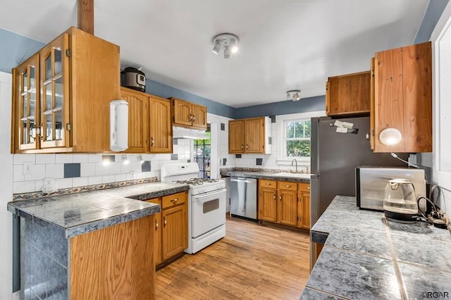 kitchen with sink, white range with gas stovetop, tasteful backsplash, stainless steel dishwasher, and light wood-type flooring