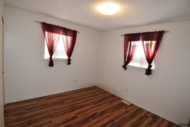 unfurnished room with dark hardwood / wood-style floors and a textured ceiling