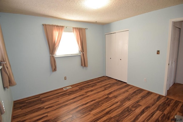 unfurnished bedroom with dark wood-type flooring, a textured ceiling, and a closet