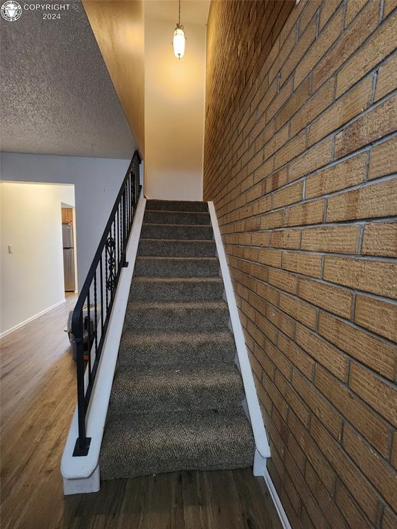 stairway featuring wood-type flooring and a textured ceiling