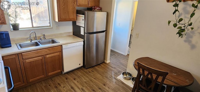 kitchen with sink, hardwood / wood-style flooring, stainless steel refrigerator, and dishwasher