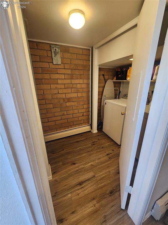 washroom featuring dark wood-type flooring, independent washer and dryer, and brick wall