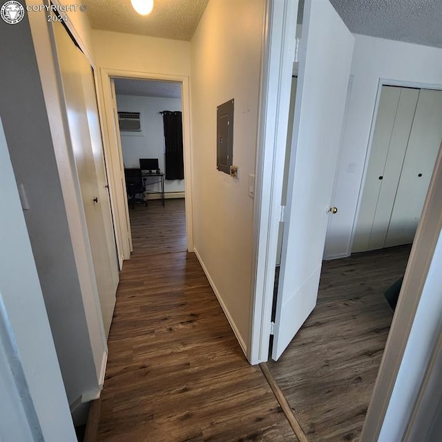 corridor featuring a textured ceiling, electric panel, and dark hardwood / wood-style flooring