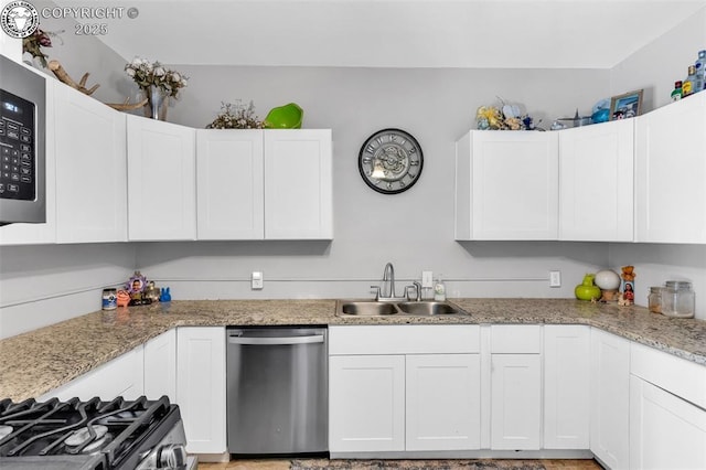 kitchen with light stone counters, stainless steel appliances, sink, and white cabinets