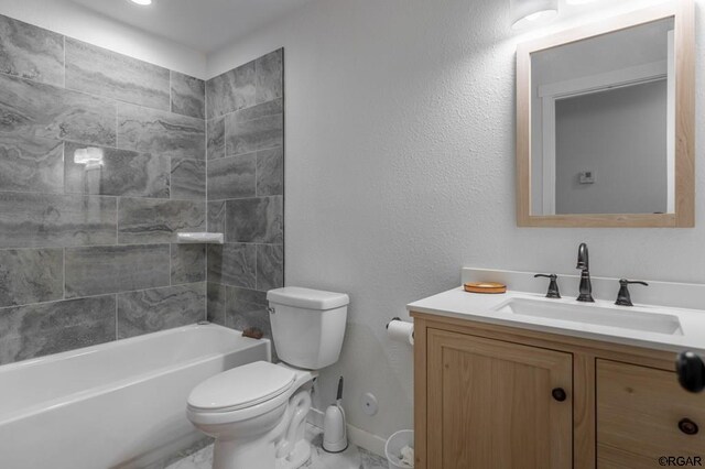 full bathroom featuring tiled shower / bath, vanity, and toilet