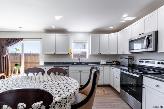 kitchen featuring appliances with stainless steel finishes, light hardwood / wood-style floors, sink, and white cabinets