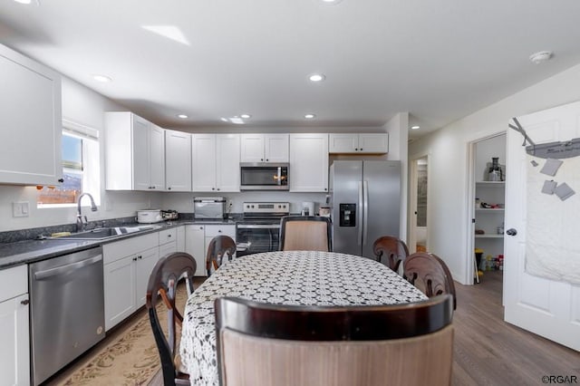 kitchen with stainless steel appliances, sink, dark wood-type flooring, and white cabinets