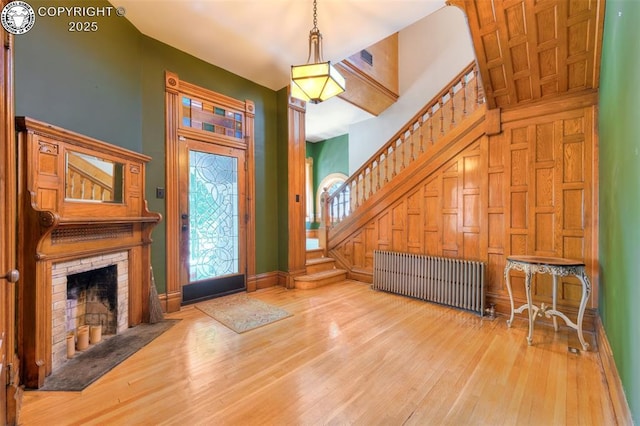417 Greenwood Ave, Canon City, CO 81212 - foyer entrance featuring radiator, stairway, wood finished floors, a fireplace with flush hearth, and a high ceiling
