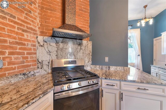 417 Greenwood Ave, Canon City, CO 81212 - kitchen with stainless steel gas range, wall chimney exhaust hood, white cabinets, light stone counters, and backsplash