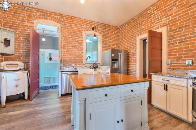 417 Greenwood Ave, Canon City, CO 81212 - kitchen featuring appliances with stainless steel finishes, wooden counters, light wood finished floors, brick wall, and a center island
