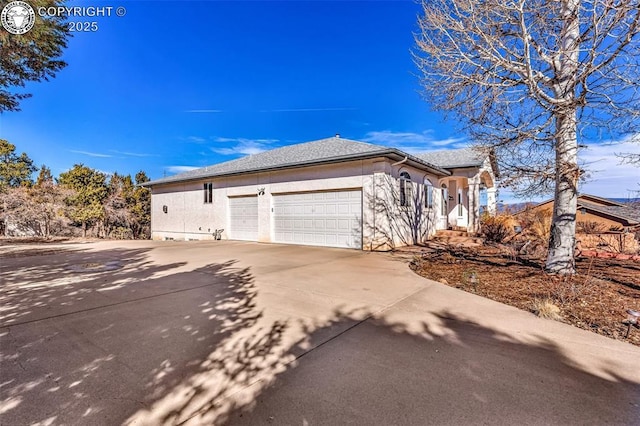 view of side of home with concrete driveway, an attached garage, and stucco siding