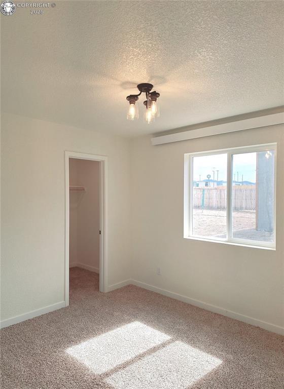 138 Jerry Dr, Westcliffe, CO 81252 - carpeted spare room featuring a notable chandelier, baseboards, and a textured ceiling
