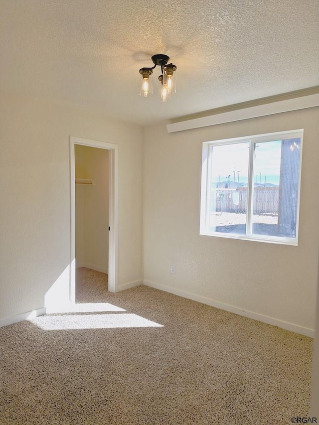 spare room featuring a textured ceiling and carpet